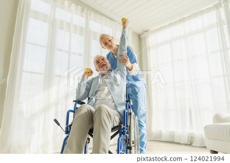 Support rehabilitation healthcare. Nurse helps old man patient in wheelchair picking up dumbbells. Paralyzed man in chair for people with disability doing sports exercise with nurse. Medical caregiver 124021994