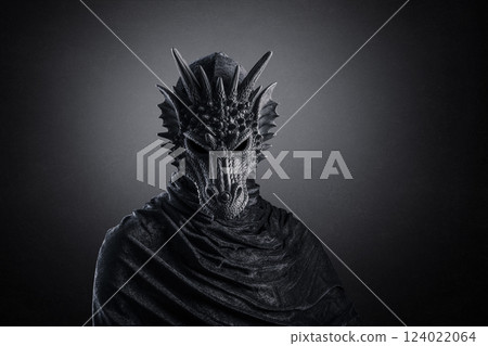 Black dragon with hooded cloak over dark misty background with clipping path 124022064
