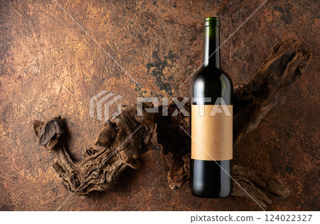 Bottle of red wine and old weathered snags on a brown vintage background. 124022327