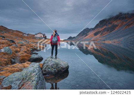 Young woman standing on a rock on alpine mountain lake. 124022425