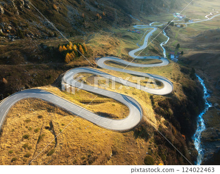 Aerial view of winding mountain road, river in alpine valley 124022463