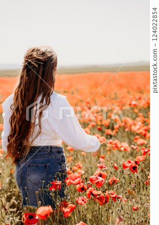Woman poppies field. Side view of a happy woman with long hair in a poppy field and enjoying the beauty of nature in a warm summer day. Woman poppies field. Side view of a happy woman with long hair in a poppy field and enjoying the beauty of nature in a warm summer day. 124022854