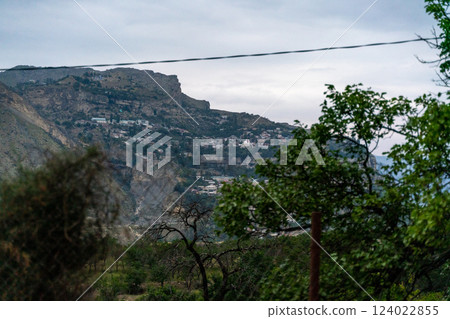 A mountain range with a city in the distance A mountain range with a city in the distance 124022855