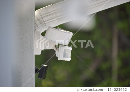Motion sensor with light detector mounted on exterior wall of private house as part of security system Motion sensor with light detector mounted on exterior wall of private house as part of security system 124023632