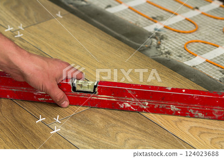 Installation of ceramic tiles and heating elements in warm tile floor. Renovation and improvement concept. 124023688
