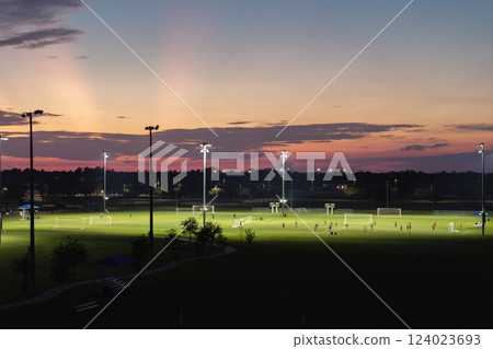 Illuminated public sports arena in North Port, Florida with people playing soccer game on grass football stadium at sunset. Outdoor activities concept Illuminated public sports arena in North Port, Florida with people playing soccer game on grass football stadium at sunset. Outdoor activities concept 124023693