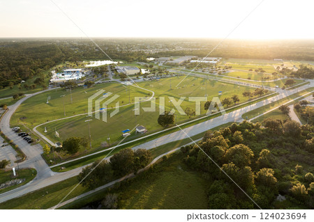 Illuminated public sports arena in North Port, Florida with people playing soccer game on grass football stadium at sunset. Outdoor activities concept 124023694