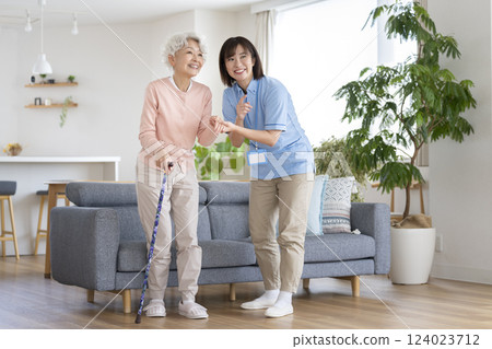 Care staff supporting a senior woman standing up 124023712