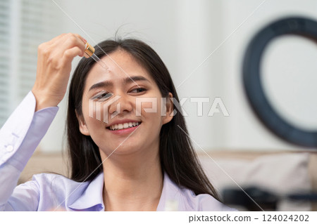 Beauty broker applying skincare serum during a live broadcast demonstration 124024202