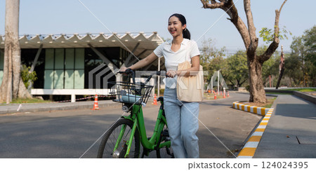 Cheerful woman with bicycle in a sunny urban setting, advocating for eco-friendly commuting. 124024395