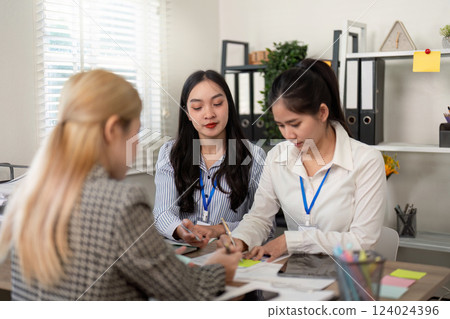 Diverse business team collaborating with notes and stationery at a desk. 124024396