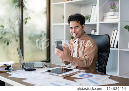 Business success unveiled a young professional engages on smartphone in modern office environment 124024434