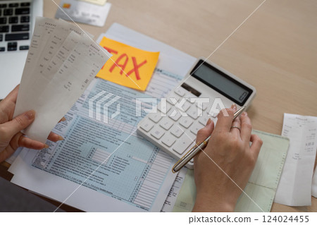 Woman calculating taxes with receipts and a calculator for financial management. 124024455