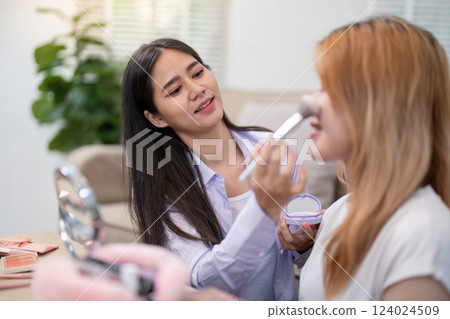 Asian friends enjoying makeup session with blush application Asian friends enjoying makeup session with blush application 124024509