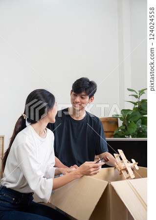 Content couple unpacking boxes and sharing smiles in their new home filled with plants 124024558