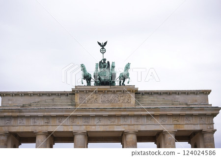 There is a statue of a horsedrawn carriage placed on top of a building 124024586