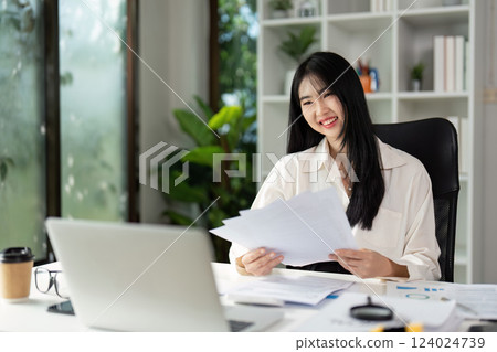 Smiling accountant reviewing tax documents and enjoying a productive workday. 124024739