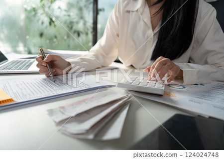 Person managing tax documents and checking information on a smartphone. 124024748