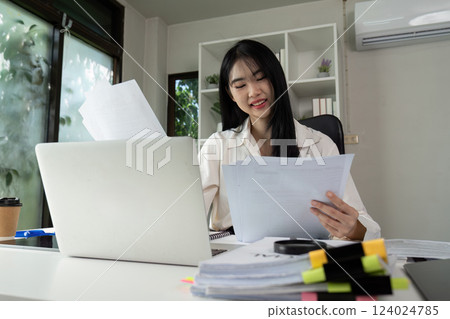 Focused accountant analyzing financial statements and preparing for tax filing at a desk. Focused accountant analyzing financial statements and preparing for tax filing at a desk. 124024785