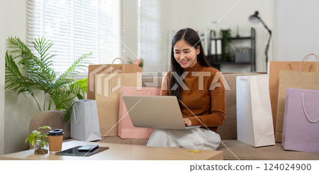 Modern shopping lifestyle. Young woman with a laptop and credit card enjoying her online shopping experience at home. 124024900