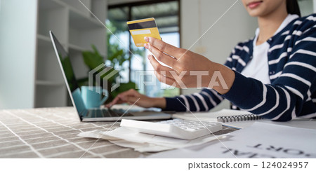 Focused woman working on a laptop at home, planning finances and managing bills efficiently. 124024957