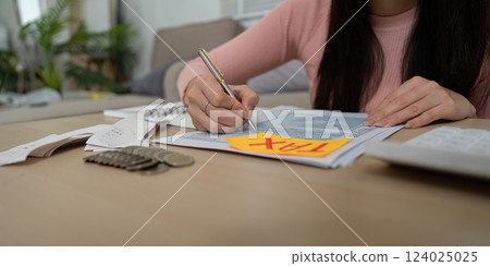 Close-up of woman writing tax details with calculator and receipts 124025025