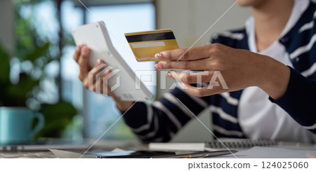 Focused woman reviewing credit card and financial documents at home. Focused woman reviewing credit card and financial documents at home. 124025060