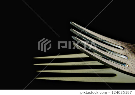 Close-up of a fork horizontally on a black surface, shadow reflection 124025197