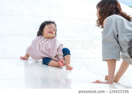 [Mother and infant sitting on giant playground equipment] 124025356