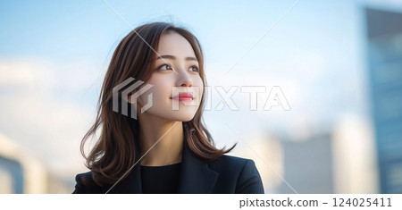 Successful young businesswoman standing outdoors and looking optimistically to the future 124025411
