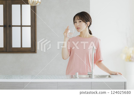 Woman drinking water in the kitchen Woman drinking water in the kitchen 124025680