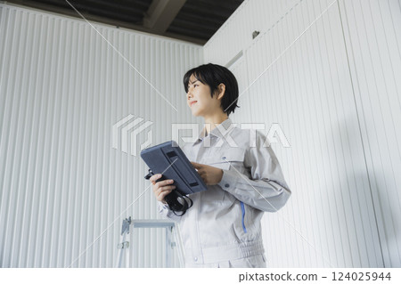 Young woman standing with a tablet in a factory 124025944