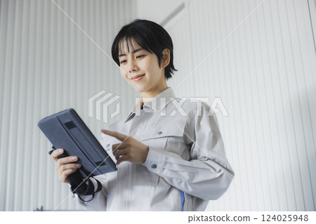 Young woman standing with a tablet in a factory 124025948