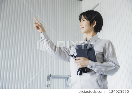 一名年輕女子站在工廠裡拿著平板電腦 124025950