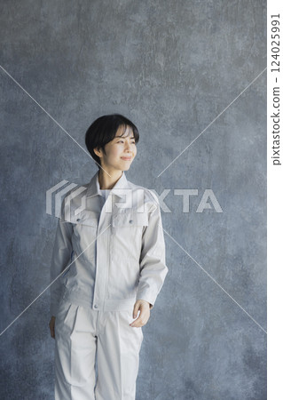 A woman in work clothes walking through a warehouse 124025991