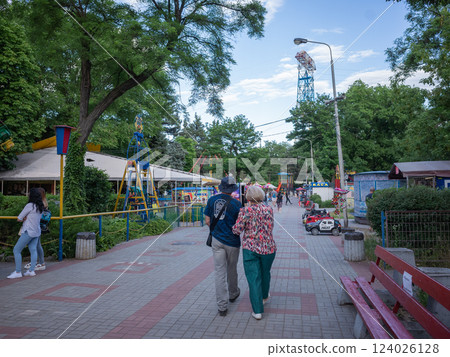 [Ukraine] Back view of an elderly couple walking along the street of an amusement park in eastern Dnipro 124026128