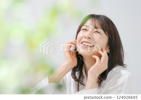 一位 50 多歲、面帶微笑、正在進行皮膚護理的女性的照片 124026685