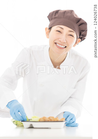 A lovely smiling part-time worker packing side dishes into a bento lunch A lovely smiling part-time worker packing side dishes into a bento lunch 124026738