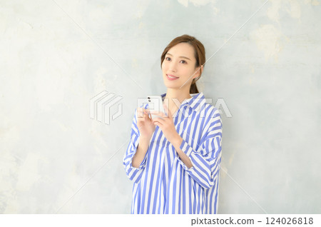 A woman standing and operating a smartphone 124026818