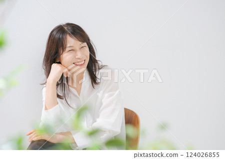 一位 50 多歲的女人坐在椅子上微笑 一位 50 多歲的女人坐在椅子上微笑 124026855