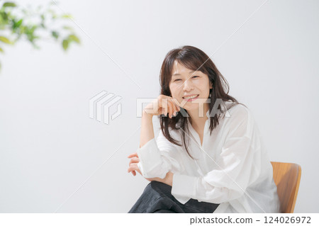 一位 50 多歲的女人坐在椅子上微笑 124026972