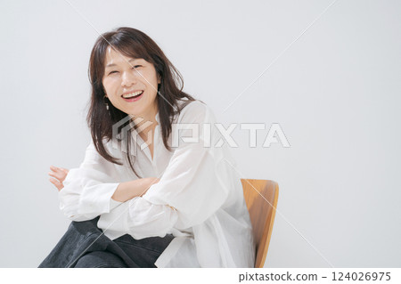 一位 50 多歲的女人坐在椅子上微笑 124026975