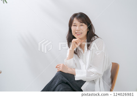 A smiling woman in her 50s sitting on a chair A smiling woman in her 50s sitting on a chair 124026981