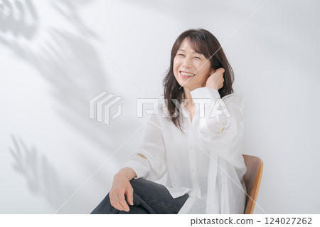 A smiling woman in her 50s sitting on a chair 124027262