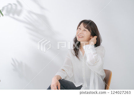 A smiling woman in her 50s sitting on a chair 124027263