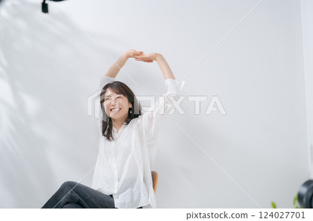 A smiling woman in her 50s stretching 124027701