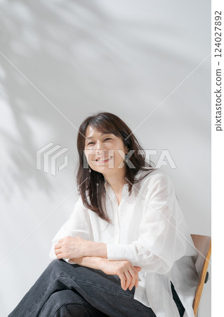 Smiling middle-aged woman sitting on a chair Smiling middle-aged woman sitting on a chair 124027892