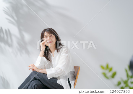 Smiling middle-aged woman sitting on a chair Smiling middle-aged woman sitting on a chair 124027893