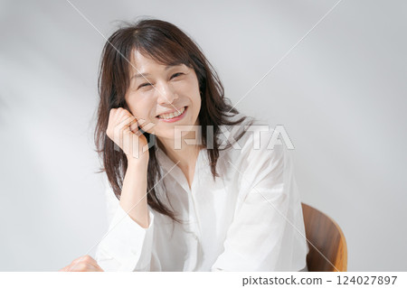 Smiling middle-aged woman sitting on a chair 124027897