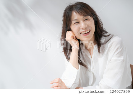 Smiling middle-aged woman sitting on a chair Smiling middle-aged woman sitting on a chair 124027899